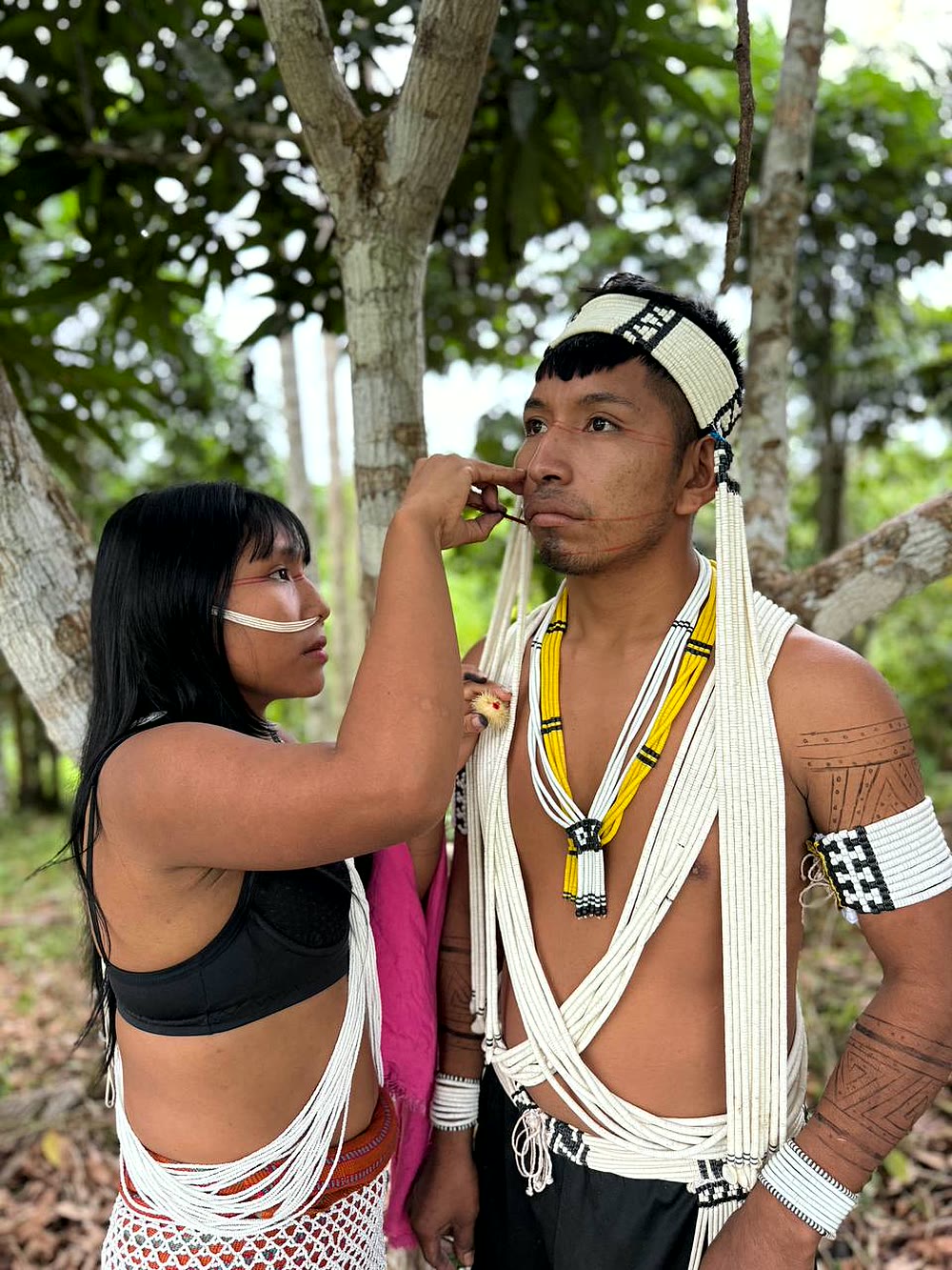 Mujer Matis pintando el rostro de un hombre con achiote en la Amazonía